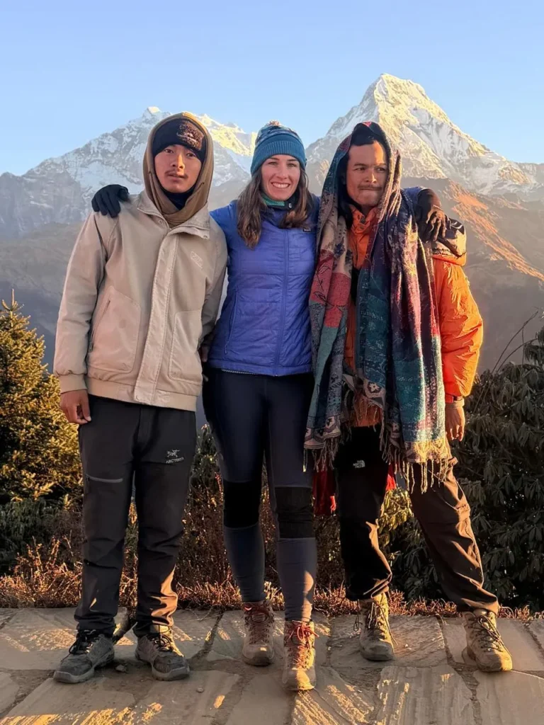 Three trekkers standing together with majestic snow-capped Himalayan peaks in the background during their Annapurna Circuit Trek with Tilicho Lake.