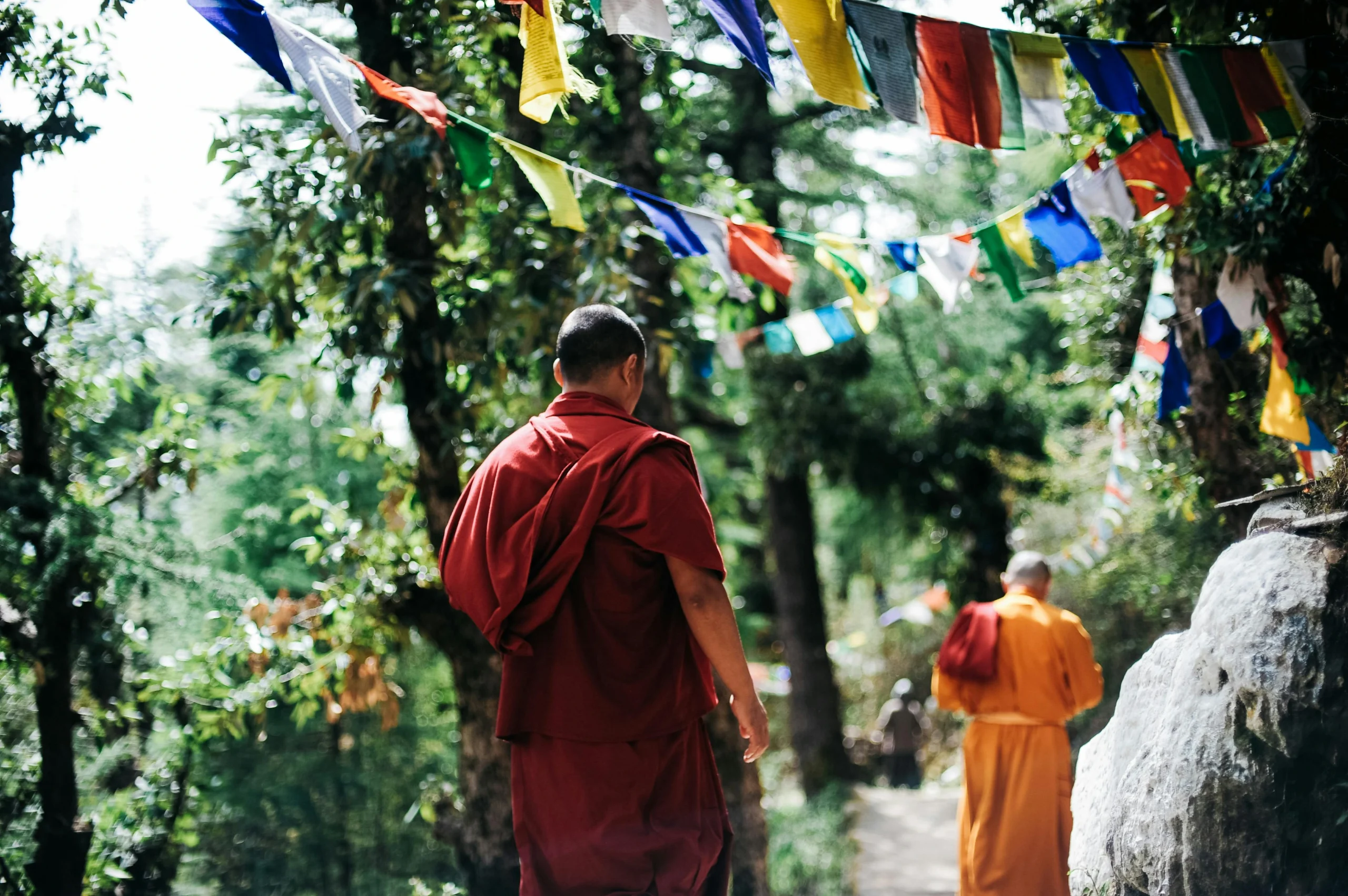 Monks walking under colorful prayer flags.l